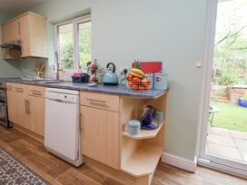 A kitchen countertop with a blue kettle a fruit basket and containers next to a dishwasher and sliding glass door at 2 Mountain View in Chirk