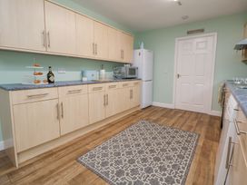 A kitchen with light wood cabinets a patterned rug on a wooden floor and white appliances at 2 Mountain View in Chirk