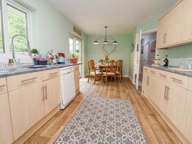 A kitchen with wooden cabinets a dining table with chairs and a patterned rug at 2 Mountain View in Chirk