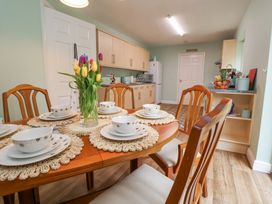 A dining table set with plates and bowls and a vase of tulips in a kitchen at 2 Mountain View in Chirk
