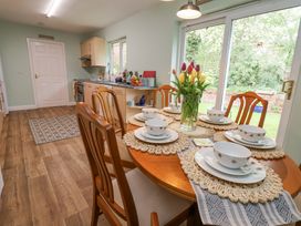 A kitchen with a wooden dining table set with bowls and plates and a vase of tulips by a glass door at 2 Mountain View in Chirk