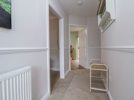 A hallway with beige carpet walls painted white and a door leading to another room at 2 Mountain View in Chirk