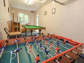 A game room with a foosball table and a small pool table with chairs and framed pictures on the walls at 2 Mountain View in Chirk