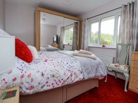 A bedroom with a floral bedspread a chair a dresser and a large mirror wardrobe at 2 Mountain View in Chirk