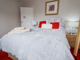 A bedroom with a bed with floral and red pillows bedside tables with lamps and folded towels on the bed at 2 Mountain View in Chirk
