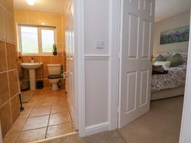 A bathroom with a sink and toilet next to a bedroom with a bed and pillows at 2 Mountain View in Chirk