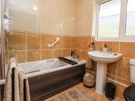 A bathroom with a bathtub a sink a window and towels at 2 Mountain View in Chirk