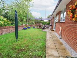 A backyard with a covered seating area a barbecue grill and plants at 2 Mountain View in Chirk