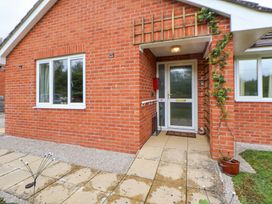 A red brick house exterior with a white door and two windows at 2 Mountain View in Chirk