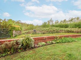 A garden with a flower bed along a low brick wall and greenery beyond at 2 Mountain View in Chirk