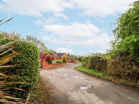 A curved gravel driveway with bushes and trees on both sides leading to a brick house at 2 Mountain View in Chirk