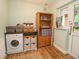 A laundry room with a washing machine and storage baskets at 2 Mountain View in Chirk