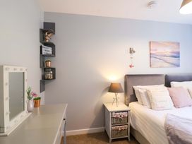 A bedroom with a bed, mirror, and shelves at Driftwood - 54 Valley Lodge, St Ann's Chapel, Cornwall
