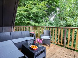 A seating area on a deck with a table and flowers at Driftwood - 54 Valley Lodge St Ann's Chapel, Cornwall