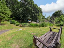 A garden view with a bench and trees at Driftwood - 54 Valley Lodge, St Ann's Chapel, Cornwall