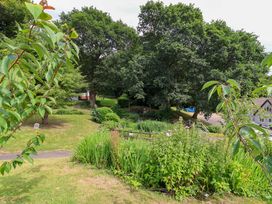 A garden with trees and a path at Driftwood - 54 Valley Lodge, St Ann's Chapel, Cornwall