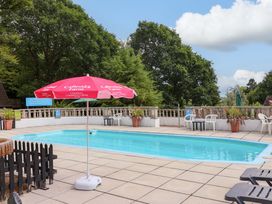 An outdoor area with a swimming pool and sun umbrella at Driftwood - 54 Valley Lodge, St Ann's Chapel, Cornwall