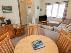 A living room with a sofa, dining table, and television at 14 Bosvigo Ruan Major near Penhale