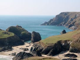 A beach with rock formations and people at the shore near Lizard