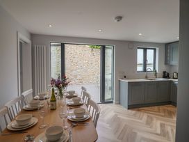 A dining room with set table and kitchen at Wagtail Cottage in Lyme Regis