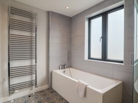 A bathroom with a bathtub and heated towel rail at Wagtail Cottage in Lyme Regis