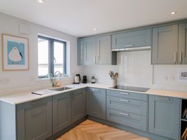 A kitchen with cabinets, sink, and window at Wagtail Cottage in Lyme Regis