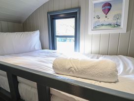 A single bed with white bedding and a rolled towel next to a small window and a framed hot air balloon picture at Dandelion in Ashby cum Fenby near Waltham