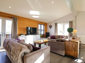 A living room with sofas coffee table TV and wooden cabinet at Angel Lodge - No 27 in Fornham St Genevieve near Bury St Edmunds