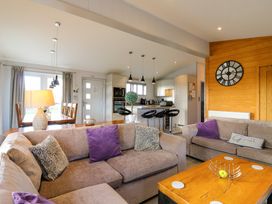 An open living room and kitchen with sofas dining table and kitchen island at Angel Lodge - No 27 in Fornham St Genevieve near Bury St Edmunds