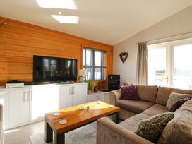 A living room with a large television on white cabinets and a brown sectional sofa at Angel Lodge - No 27 in Fornham St Genevieve near Bury St Edmunds