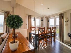 A dining area with wooden table and chairs and a potted plant on a sideboard at Angel Lodge - No 27 in Fornham St Genevieve near Bury St Edmunds