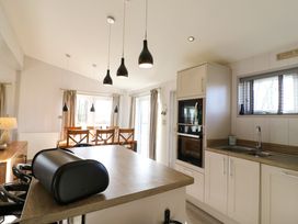 A kitchen and dining area with a countertop island and wooden dining table at Angel Lodge - No 27 in Fornham St Genevieve near Bury St Edmunds