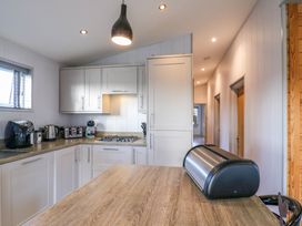 A kitchen with white cabinets a gas stove countertop appliances and a bread box on a wooden island at Angel Lodge - No 27 in Fornham St Genevieve near Bury St Edmunds