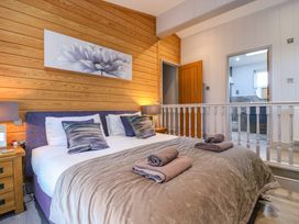 A bedroom with a bed folded towels on a blanket and a wooden wall at Angel Lodge - No 27 in Fornham St Genevieve near Bury St Edmunds