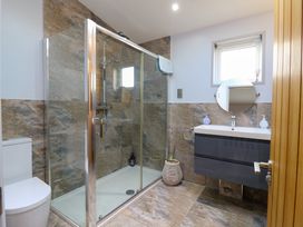 A bathroom with a glass shower enclosure a toilet a sink with a round mirror and a small window at Angel Lodge - No 27 in Fornham St Genevieve near Bury St Edmunds