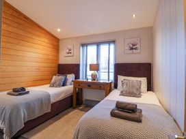 A bedroom with two single beds a wooden table and a window at Angel Lodge - No 27 in Fornham St Genevieve near Bury St Edmunds