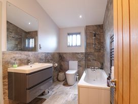 A bathroom with a bathtub shower combination a toilet a sink with a cabinet and a window at Angel Lodge - No 27 Fornham St Genevieve near Bury St Edmunds