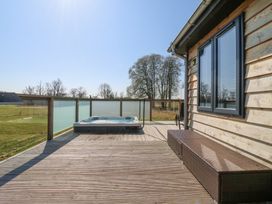 A wooden deck with a hot tub bench and glass railing at Angel Lodge - No 27 in Fornham St Genevieve near Bury St Edmunds