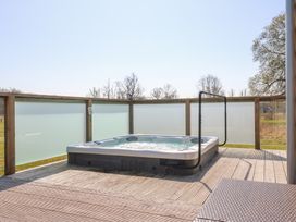 A hot tub on a wooden deck with frosted glass panels enclosing the area at Angel Lodge - No 27 in Fornham St Genevieve near Bury St Edmunds