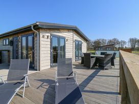 A wooden deck with outdoor chairs and a table outside a wooden building at Angel Lodge - No 27 in Fornham St Genevieve near Bury St Edmunds