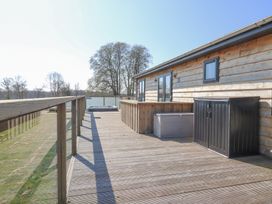 A wooden deck with railing a hot tub and storage boxes at Angel Lodge  No 27 Fornham St Genevieve near Bury St Edmunds