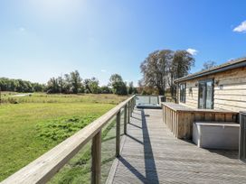 An outdoor deck with a wooden cabin and hot tub at Angel Lodge - No 27 Fornham St Genevieve near Bury St Edmunds