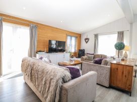 A living room with a television, sofas and a wooden table at Angel Lodge - No 27 near Bury St Edmunds