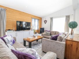 A living room with a television, sofa, and wooden table at Angel Lodge - No 27 in Fornham St Genevieve near Bury St Edmunds