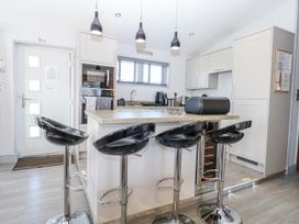 A kitchen with bar stools and modern appliances at Angel Lodge - No 27 Fornham St Genevieve near Bury St Edmunds