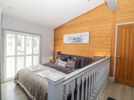 A bedroom with a bed and sliding doors at Angel Lodge - No 27, Fornham St Genevieve near Bury St Edmunds
