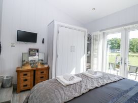 A bedroom with a bed and TV at Angel Lodge - No 27 in Fornham St Genevieve near Bury St Edmunds