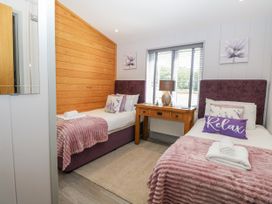 A bedroom with two beds and a wooden table at Angel Lodge - No 27 Fornham St Genevieve near Bury St Edmunds