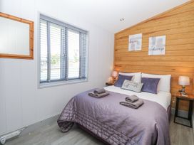 A bedroom with a bed, nightstand, and mirror at Angel Lodge - No 27 Fornham St Genevieve near Bury St Edmunds