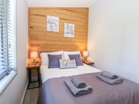 A bedroom with a double bed and wooden wall at Angel Lodge - No 27, Fornham St Genevieve near Bury St Edmunds